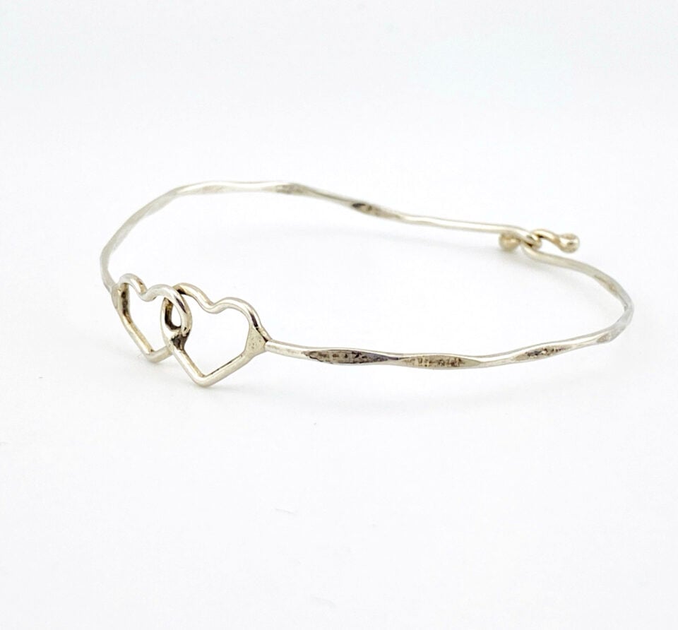 Hand wrought sterling silver cuff bracelet with hammered finish and interlocking double heart centerpiece