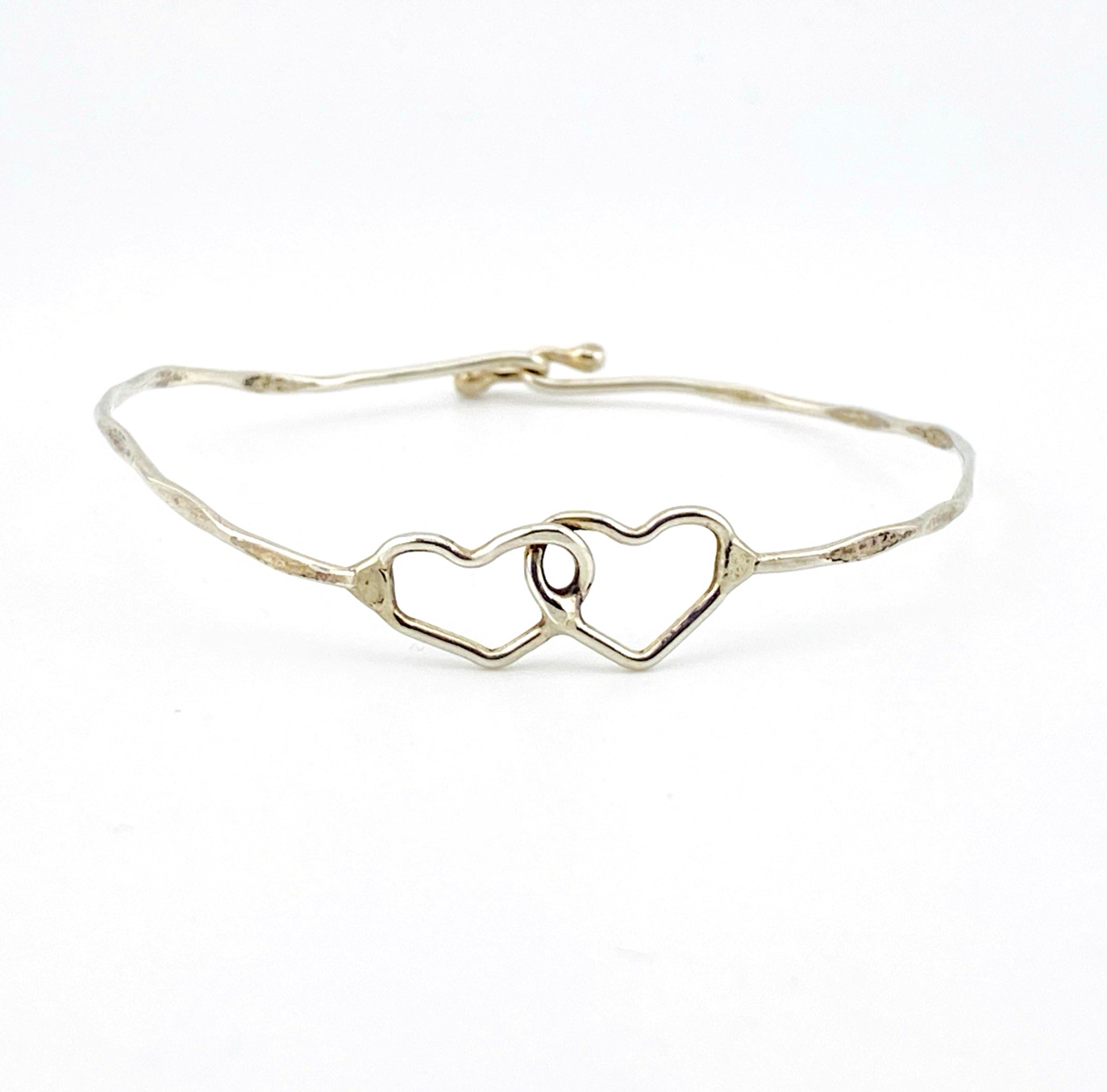 Hand wrought sterling silver cuff bracelet with hammered finish and interlocking double heart centerpiece