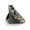 Profile view of Black rhodium sterling silver statement ring with gold coral branch design and pear-shaped amethyst color stones in an elongated oval silhouette