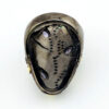 Black rhodium sterling silver statement ring with gold accents, green cubic zirconia, and pear-shaped amethyst stones in an elongated modernist design