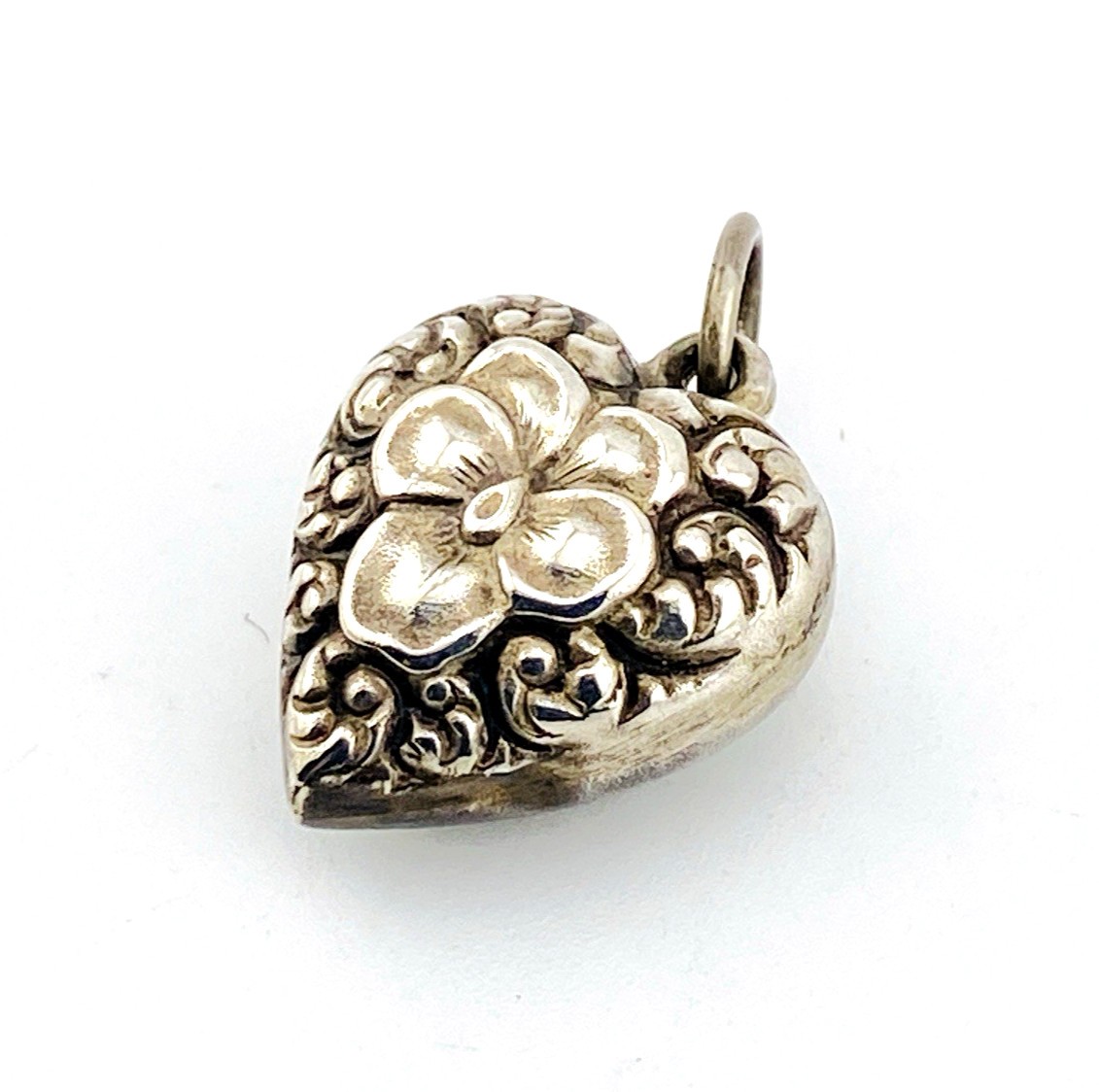 Victorian sterling silver puffy heart pendant with repoussé scrollwork, applied pansy flower, and engraved initials on the back.