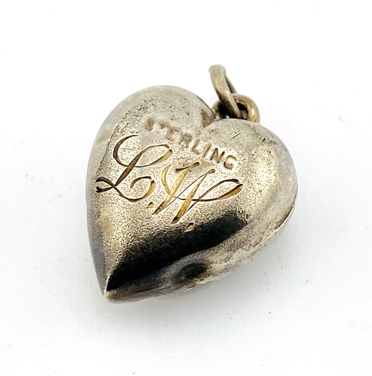 Victorian sterling silver puffy heart pendant with repoussé scrollwork, applied pansy flower, and engraved initials on the back.