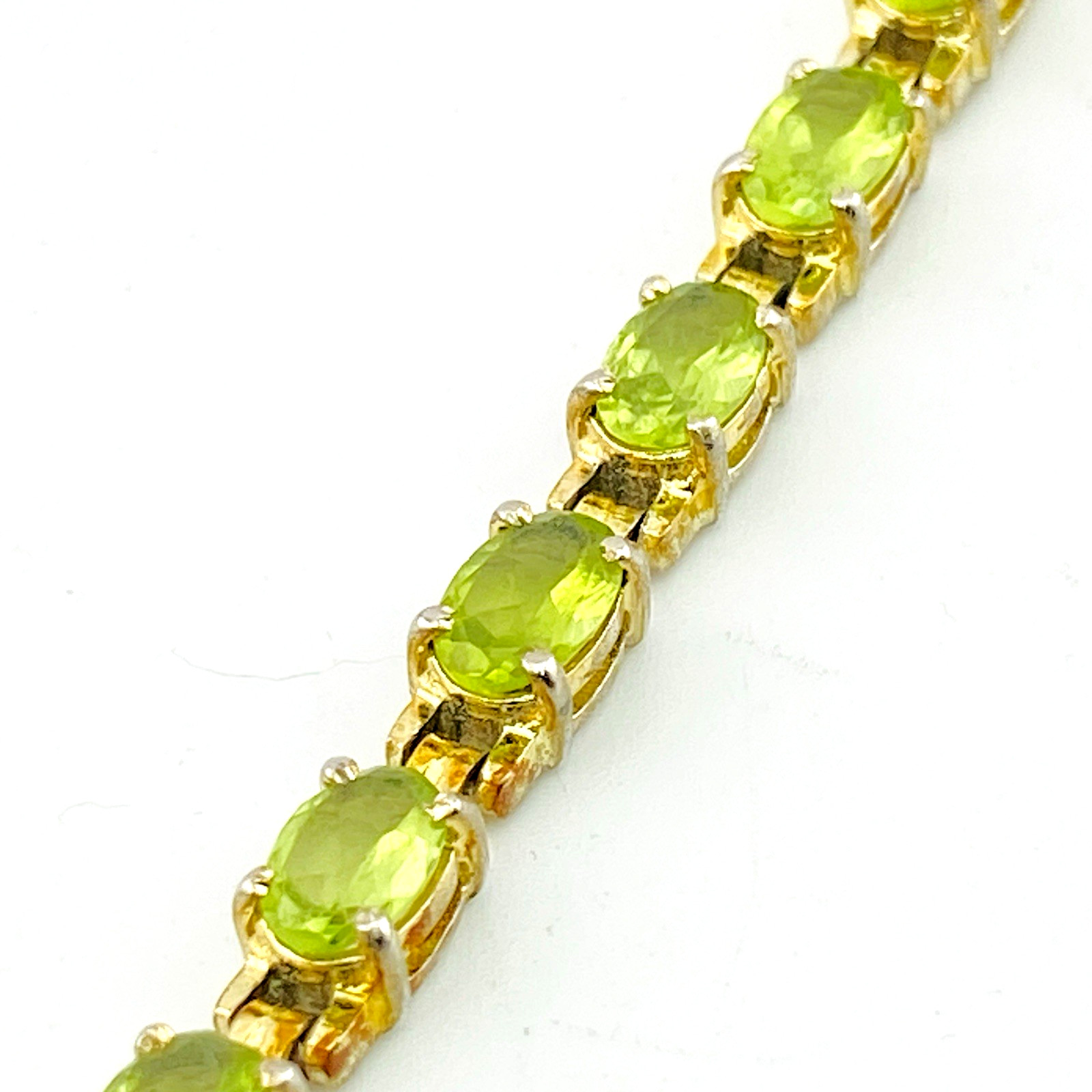 Vintage gold over sterling silver line bracelet with twenty oval faceted peridot gemstones arranged in a continuous row