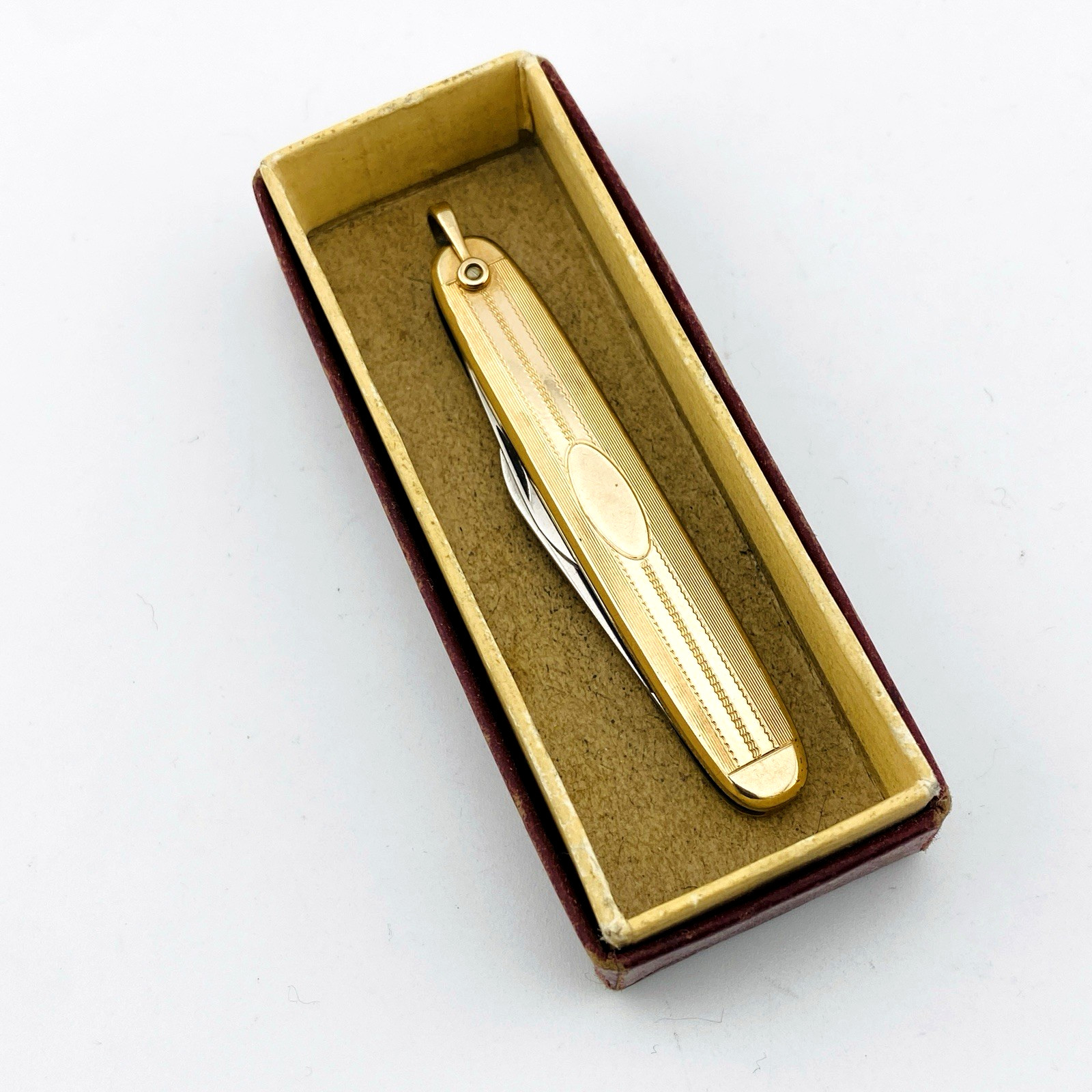 Vintage Hayward gold filled elongated oval pocket knife with engraved pin-stripe texture, blank cartouche, stainless blades, and original box.