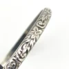 Antique P&H sterling silver bangle bracelet with carved scrolls, vines, leaves, and forget-me-not flowers.