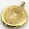 Antique Hayward 1/20 12K gold filled round photo locket with chased shield cover, floral garland, pinstripe back, and interior photo frames