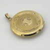 Antique Hayward 1/20 12K gold filled round photo locket with chased shield cover, floral garland, pinstripe back, and interior photo frames