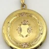 Antique Hayward 1/20 12K gold filled round photo locket with chased shield cover, floral garland, pinstripe back, and interior photo frames