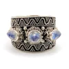 Vintage India sterling silver cigar band ring with three faceted blue flash moonstones and ornate raised silverwork.