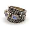 Vintage India sterling silver cigar band ring with three faceted blue flash moonstones and ornate raised silverwork.