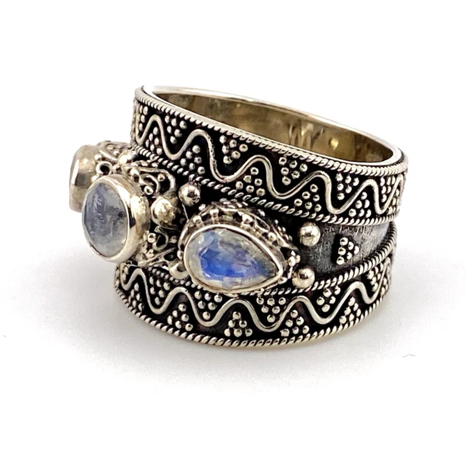 Vintage India sterling silver cigar band ring with three faceted blue flash moonstones and ornate raised silverwork.