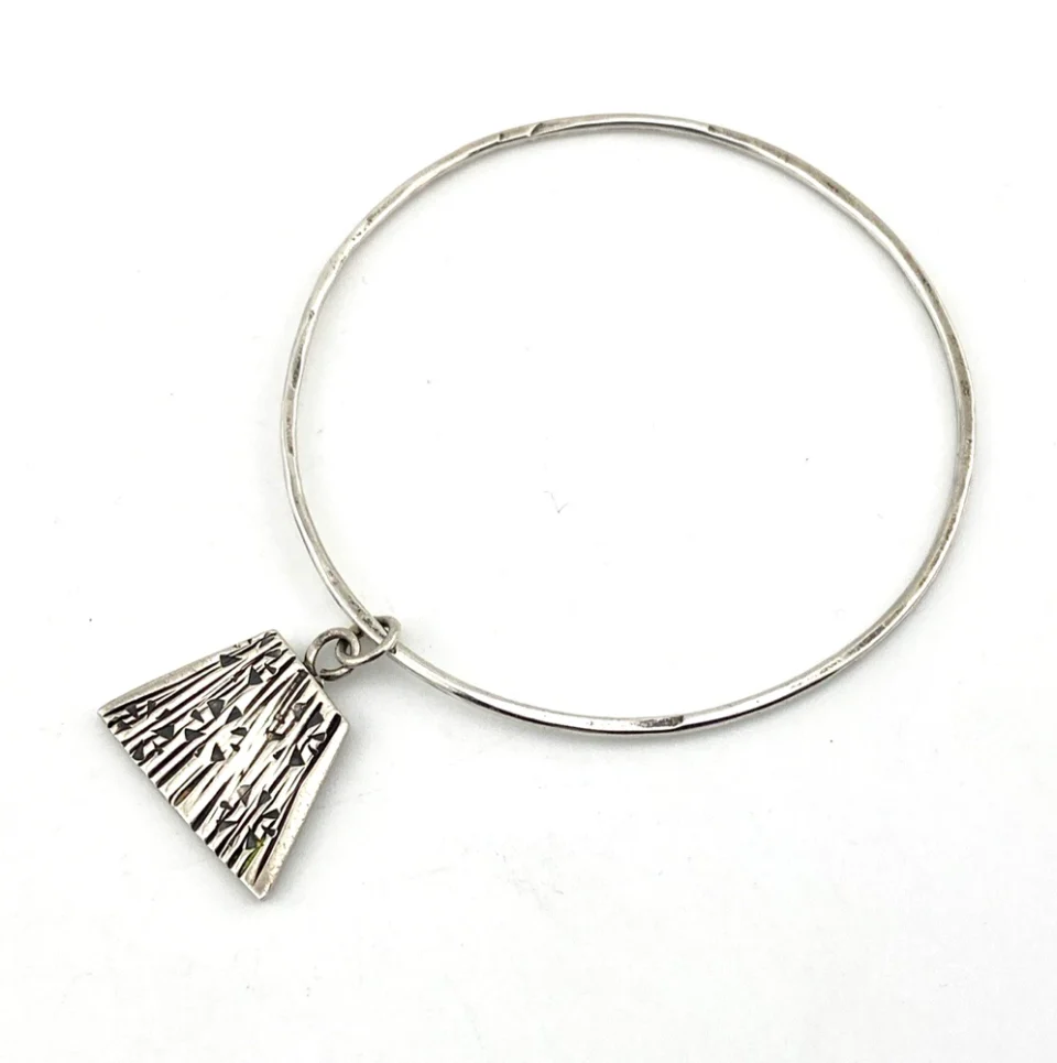 Hand wrought sterling silver studio bangle bracelet with trapezoid charm and organic stamped texture.
