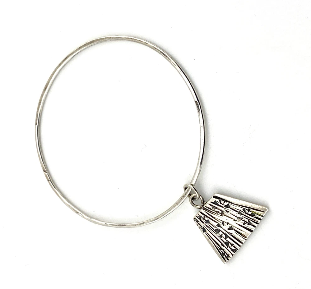 Hand wrought sterling silver studio bangle bracelet with trapezoid charm and organic stamped texture.