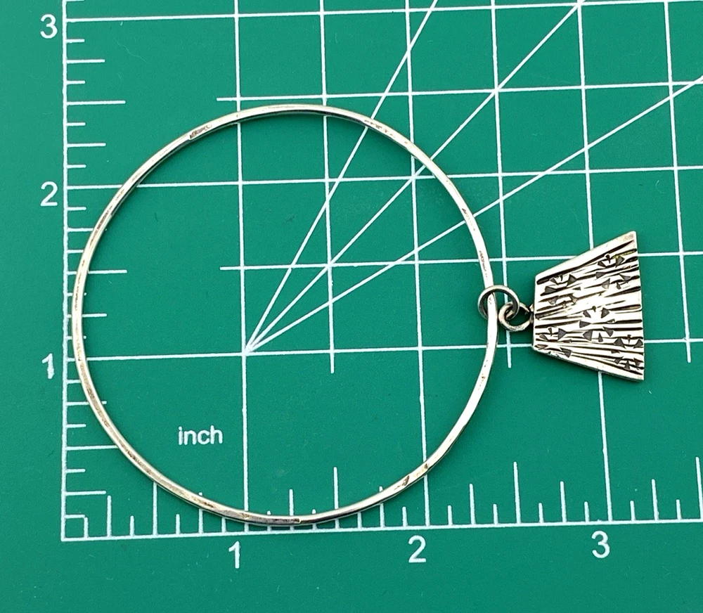 Hand wrought sterling silver studio bangle bracelet with trapezoid charm and organic stamped texture.
