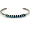 Vintage sterling silver cuff bracelet with eleven small turquoise snake-eye cabochons.