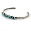 Vintage sterling silver cuff bracelet with eleven small turquoise snake-eye cabochons.