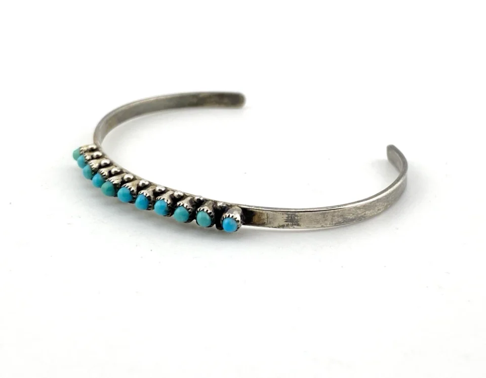 Vintage sterling silver cuff bracelet with eleven small turquoise snake-eye cabochons.