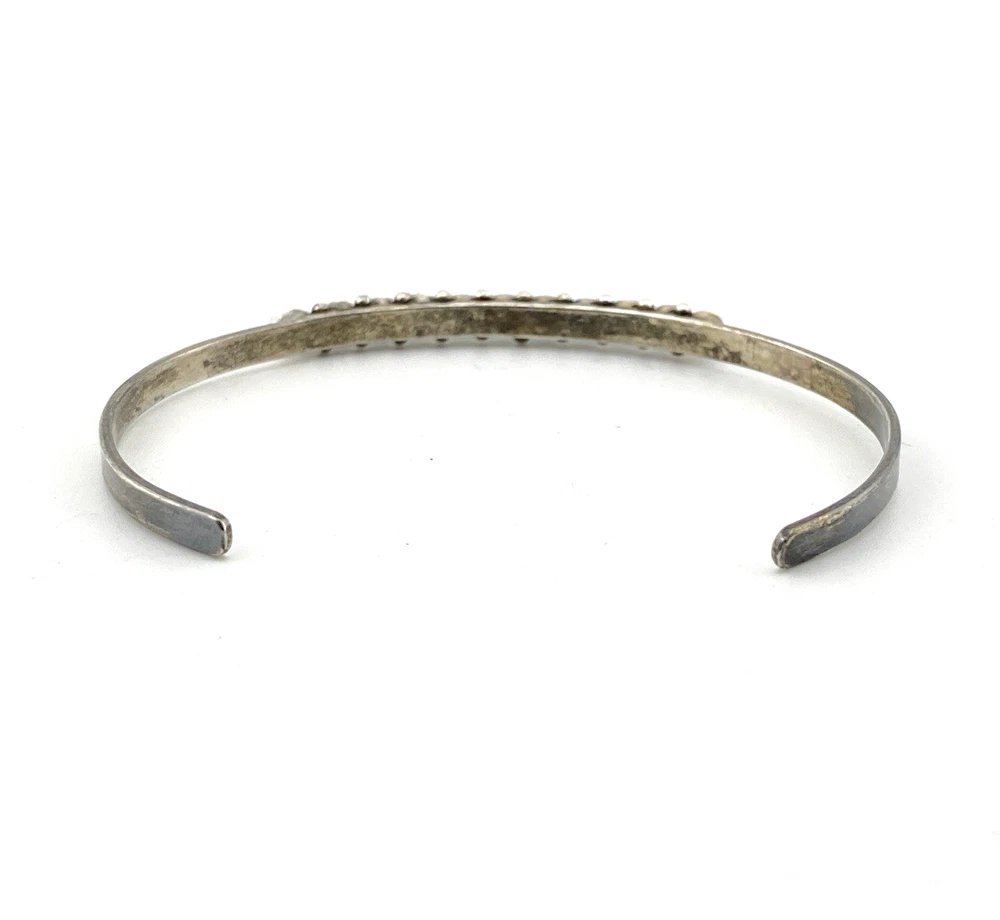 Vintage sterling silver cuff bracelet with eleven small turquoise snake-eye cabochons.
