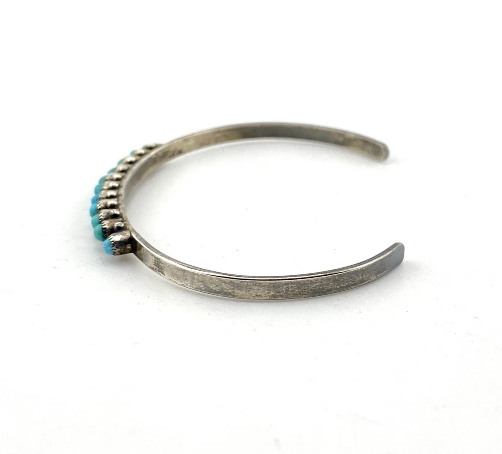 Vintage sterling silver cuff bracelet with eleven small turquoise snake-eye cabochons.
