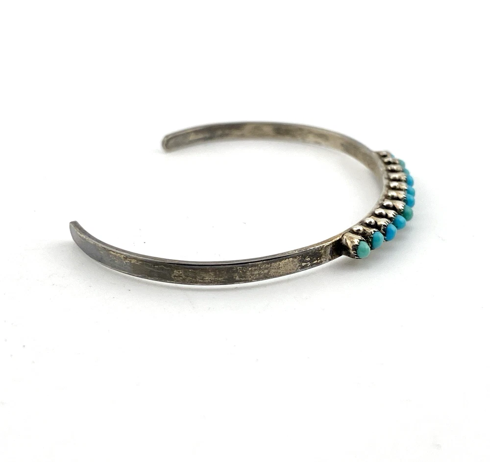 Vintage sterling silver cuff bracelet with eleven small turquoise snake-eye cabochons.