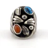 Vintage old pawn style sterling silver ring with turquoise and coral cabochons, raised silver details, and dark patina.