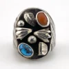 Vintage old pawn style sterling silver ring with turquoise and coral cabochons, raised silver details, and dark patina.