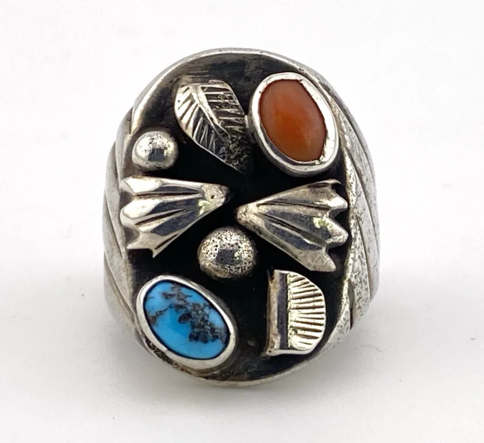 Vintage old pawn style sterling silver ring with turquoise and coral cabochons, raised silver details, and dark patina.