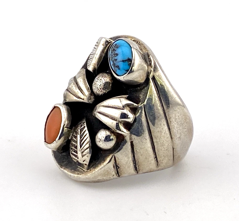 Vintage old pawn style sterling silver ring with turquoise and coral cabochons, raised silver details, and dark patina.