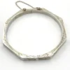 Vintage sterling silver octagonal hinged bangle bracelet with engraved details and safety chain.