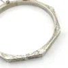 Vintage sterling silver octagonal hinged bangle bracelet with engraved details and safety chain.
