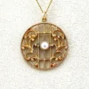 Antique Edwardian round openwork pendant necklace in warm rose gold filled with a likely natural pearl center on a 16-inch chain.