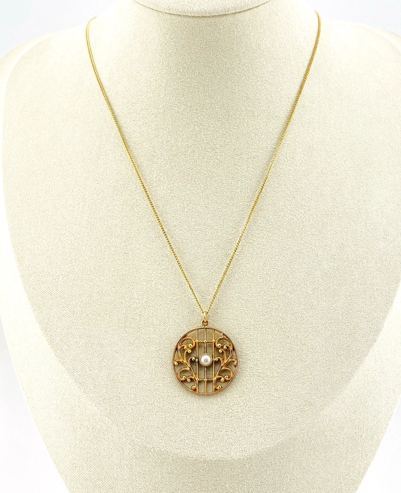 Antique Edwardian round openwork pendant necklace in warm rose gold filled with a likely natural pearl center on a 16-inch chain.