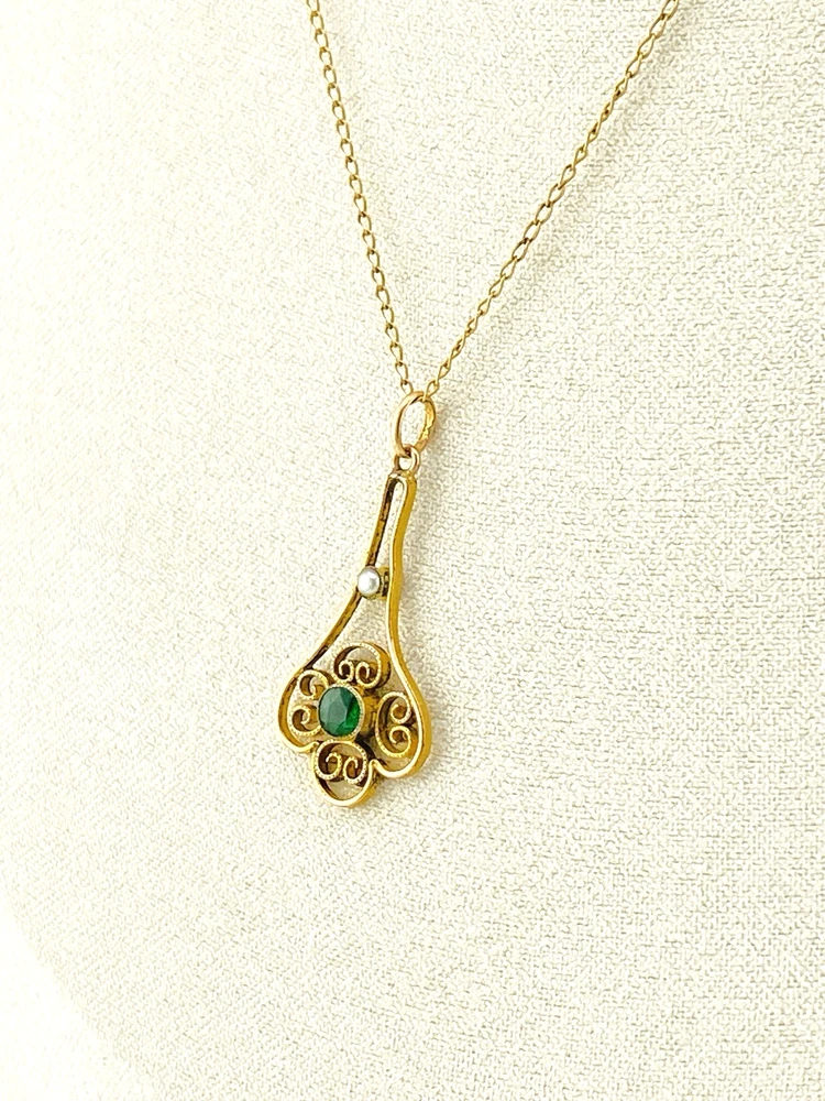 Vintage lavaliere pendant necklace with a faceted green glass stone, genuine pearl accent, and 12K gold filled chain.