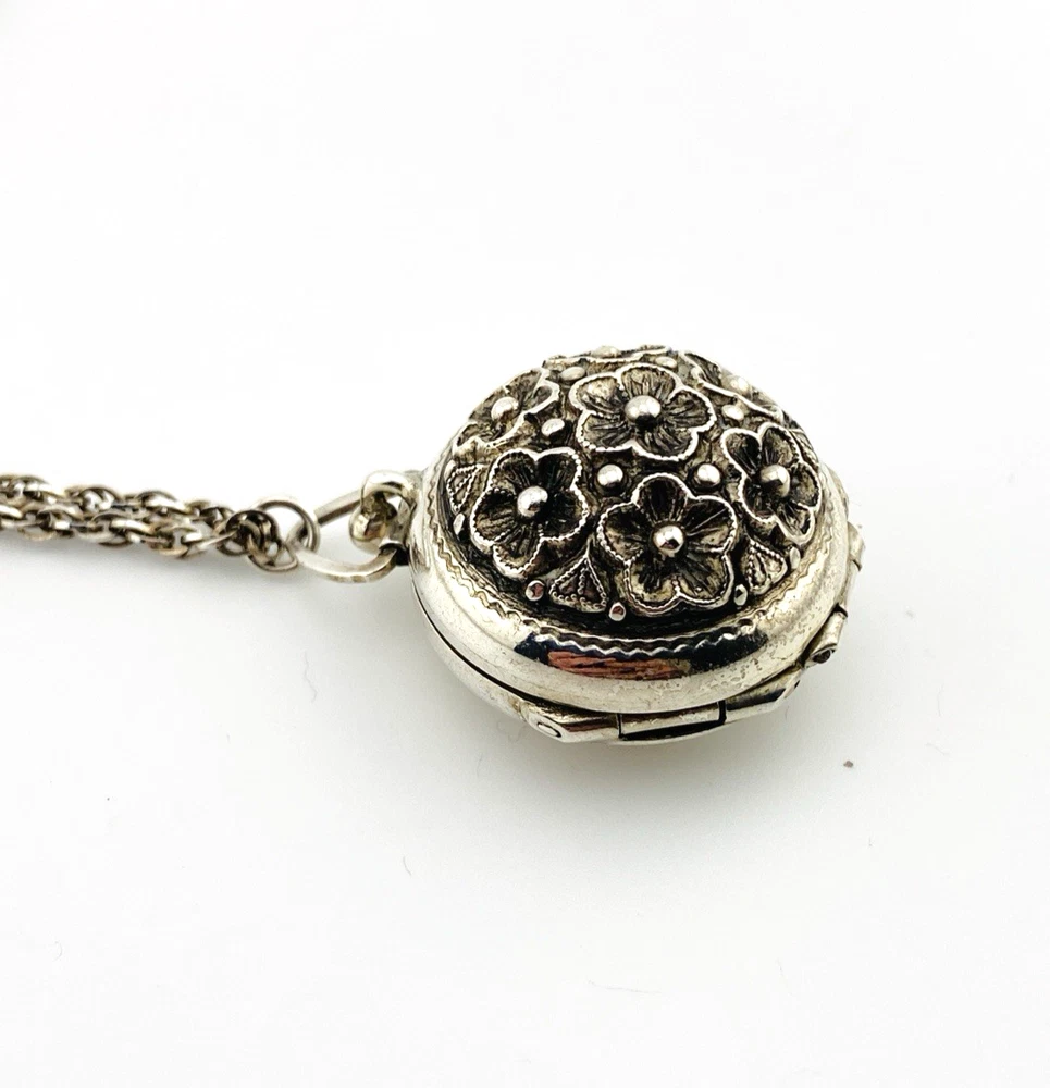 WWII-era sterling silver forget-me-not locket opened to reveal four original family photographs