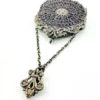 Antique silver-colored chatelaine purse with openwork metal, purple silk lining, fringe, and fleur-de-lis belt clip