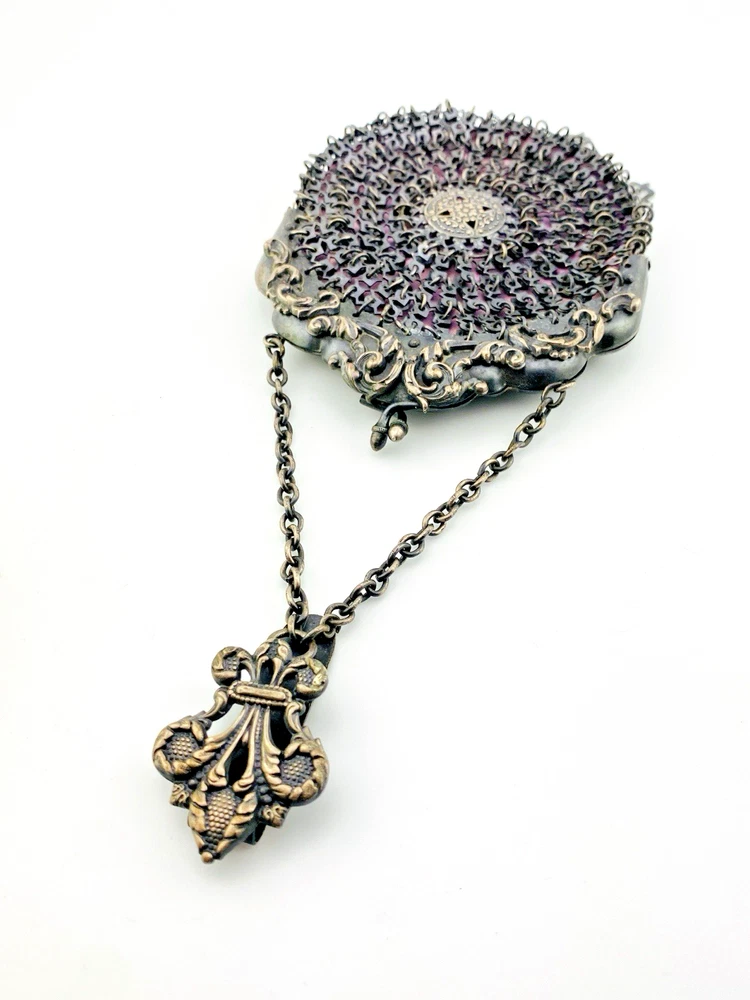 Antique silver-colored chatelaine purse with openwork metal, purple silk lining, fringe, and fleur-de-lis belt clip