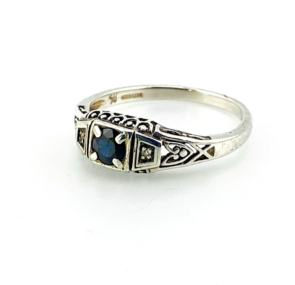 Sterling silver ring with a round blue sapphire, diamond accents and openwork shoulders