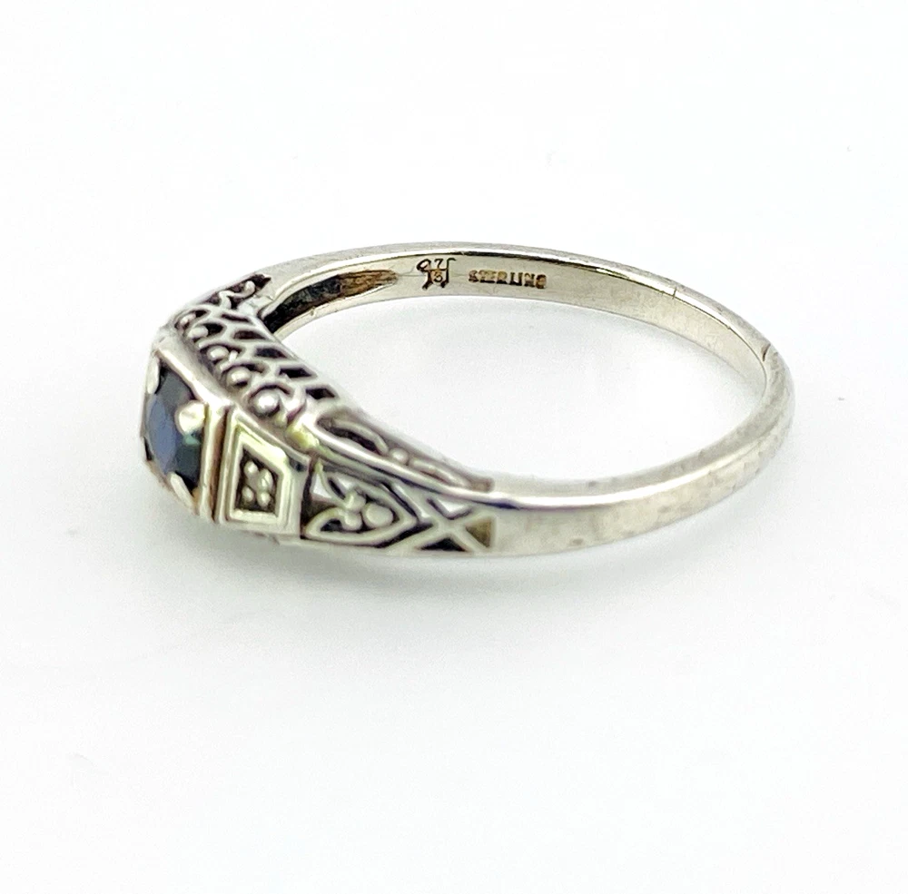Sterling silver ring with a round blue sapphire, diamond accents and openwork shoulders