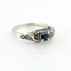 Sterling silver ring with a round blue sapphire, diamond accents and openwork shoulders