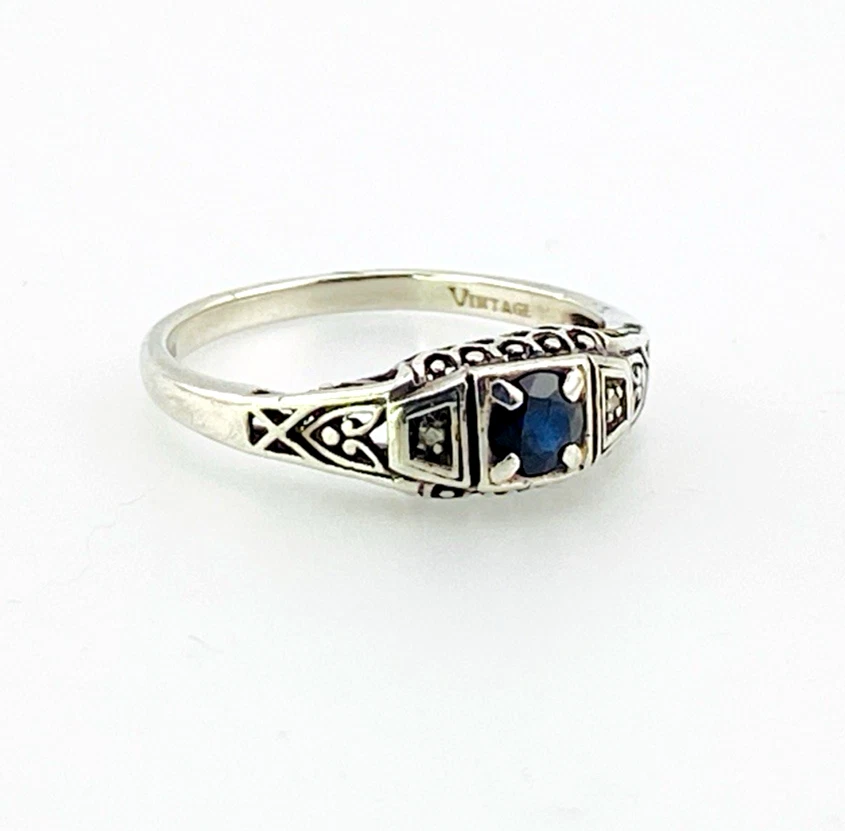 Sterling silver ring with a round blue sapphire, diamond accents and openwork shoulders