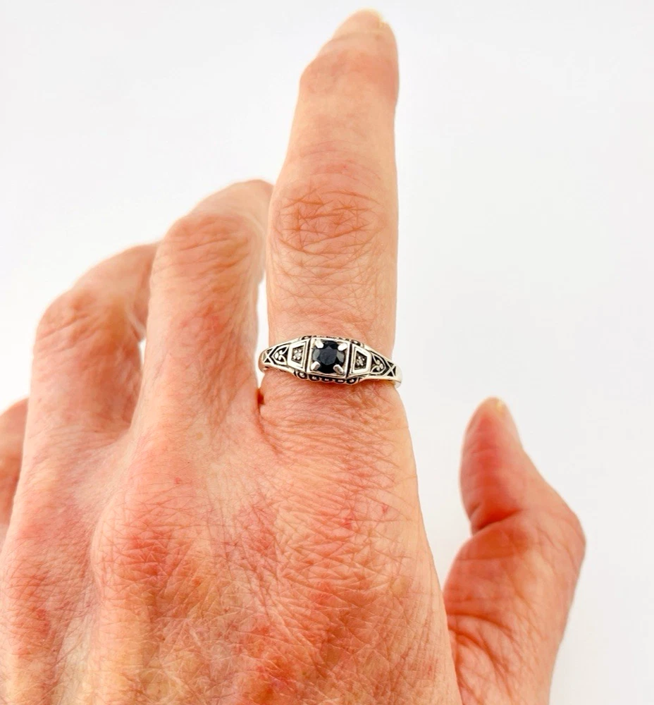 Sterling silver ring with a round blue sapphire, diamond accents and openwork shoulders