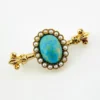 Late Victorian 14k gold brooch with oval turquoise, natural seed-pearl halo, and fleur-de-lis ends