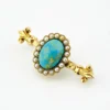 Late Victorian 14k gold brooch with oval turquoise, natural seed-pearl halo, and fleur-de-lis ends