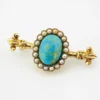 Late Victorian 14k gold brooch with oval turquoise, natural seed-pearl halo, and fleur-de-lis ends