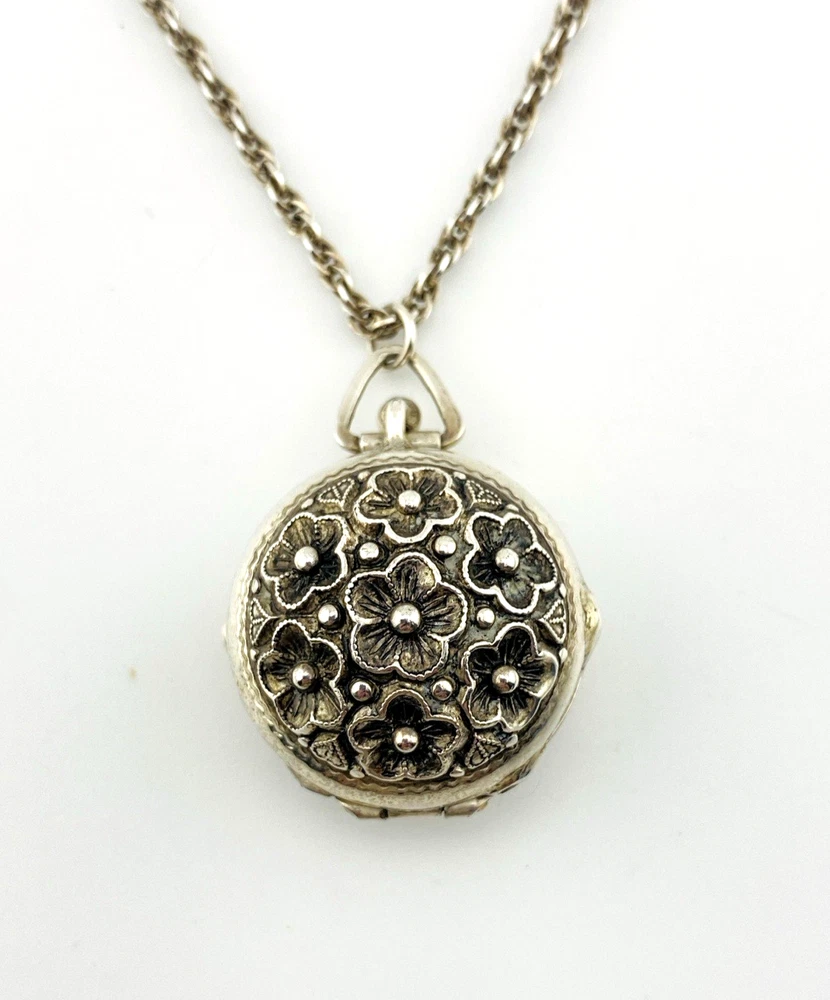 WWII-era sterling silver forget-me-not locket opened to reveal four original family photographs