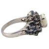 Oval natural opal surrounded by tiered blue sapphires in a white gold plated sterling silver princess cluster ring