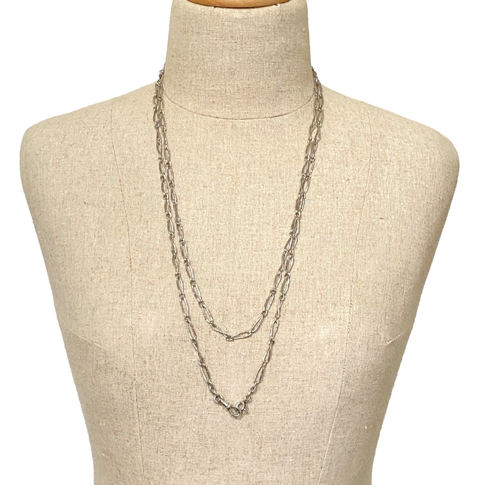 Long 800 silver guard chain with ribbon-bound sheaf links, swivel dog clip, and spring ring, shown doubled on a mannequin