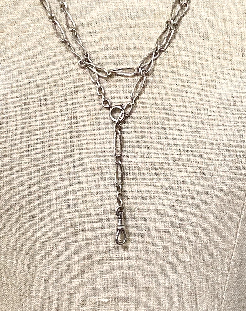 Long 800 silver guard chain with ribbon-bound sheaf links, swivel dog clip, and spring ring, shown doubled on a mannequin