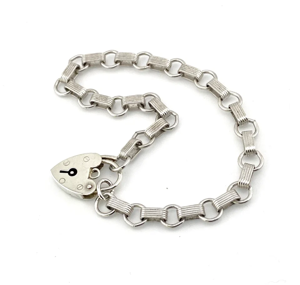 Slender sterling silver gate-link bracelet with ribbed bars, open connectors, and a heart padlock clasp