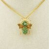 Gold-plated sterling silver bee brooch with a green gemstone-set body, clear cubic zirconia accent, raised patterned wings, and textured legs.